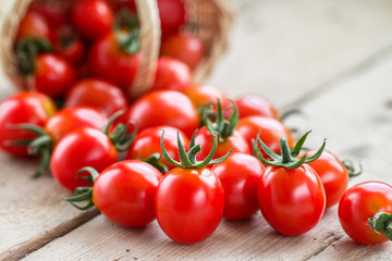 Small red cherry tomatoes spill out of a wicker basket
