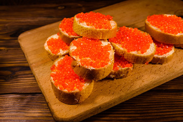 Sandwiches with red caviar on a cutting board