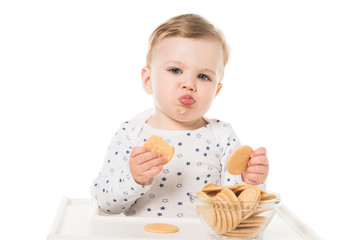 adorable baby boy eating cookies sitting in highchair isolated on white background