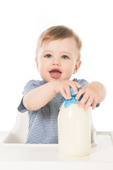 adorable baby boy with bottle of milk sitting in highchair isolated on white background