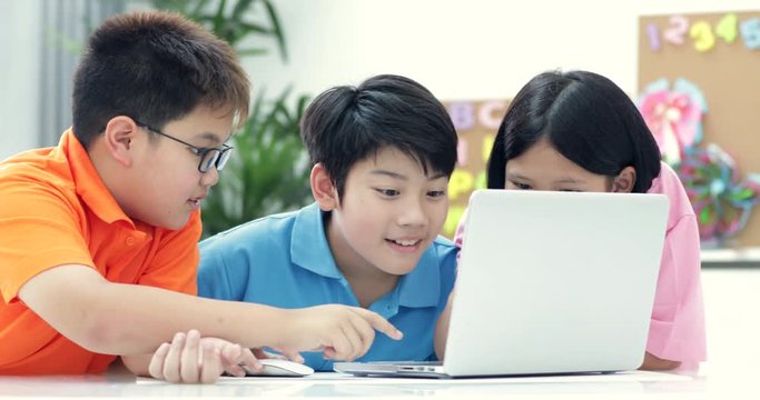 Cute Asian children using laptop together.