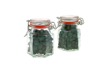 Algae spirulina tablets. pills of spirulina in two transparent glass jars isolated on white background.Super food concept. seaweed in tablets.nature Supplement. Food supplements 