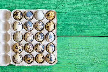 Fresh raw quail eggs in packaging on natural wooden background, close-up flat lay, copy space
