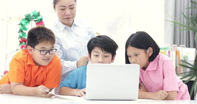 Asian woman teacher and Cute Asian children using laptop computer together.