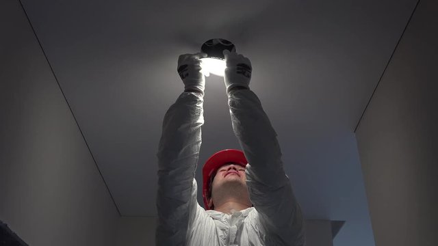 young worker man installing led lights on ceiling hole