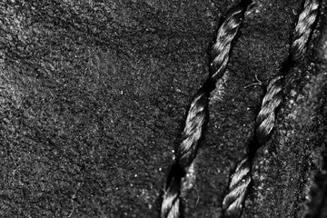 Thread seam on black leather material as background