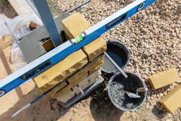 man builds a brick wall at a construction site