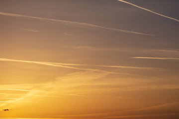 Naklejka na ściany i meble Traces of aircraft in the sky at sunset