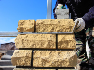 man builds a brick wall at a construction site