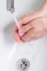Fototapeta premium personal hygiene process of washing hands with soap in a wash basin under the tap of water