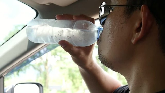 Man is drinking water while driving car dangerously - people in car moving doing multitasking dangerous behave concept