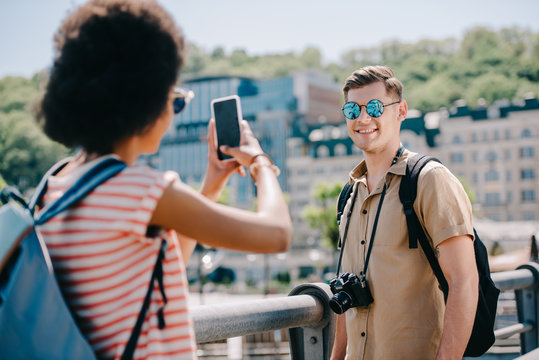 female traveler taking picture of boyfriend on smartphone