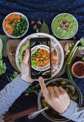Smartphone photography of food for lunch or dinner. Woman hands takes phone photo of food for social media and blogging publications. Raw vegan vegetarian healthy food