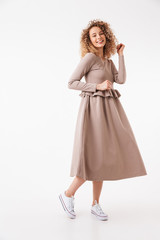 Full length image of Cheerful blonde curly woman in dress