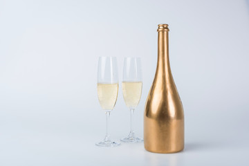 golden bottle of champagne and glasses on white