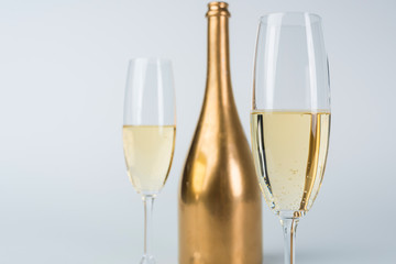 golden bottle of champagne and glasses isolated on white