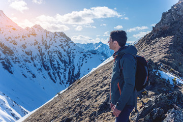 Hiker stands on top and looks up at the sky and snowy mountains around. Concept of travel and achieve the goal