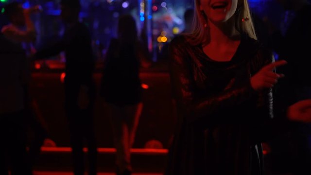 Young happy female dancing and singing at night club, enjoying weekend party