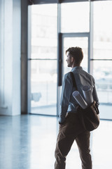 side view of architect with blueprints in bag standing in empty building