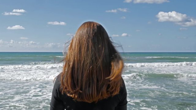 Girl with long red hair in the beach, sea breeze play with hair, daytime shot in Tel Aviv.