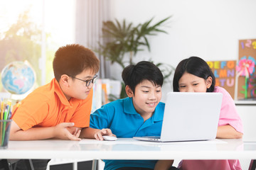 Obraz premium Cute Asian children using laptop together.