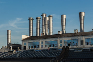 Moscow. shiny metal pipes protrude from the factory building against a clear blue sky