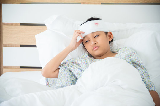 Young asian girl with bandage on head lying on bed in hospital