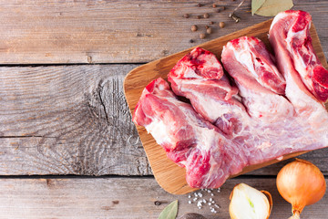 Raw pork on bone for soup (broth) with spices on a wooden table, top view, copy space