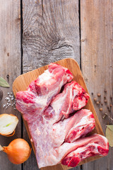 Raw pork on bone for soup (broth) with spices on a wooden table, top view, copy space