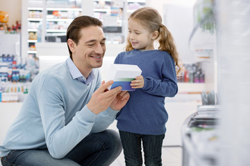 Listen attentively. Cheerful jovial man and girl holding medication and smiling