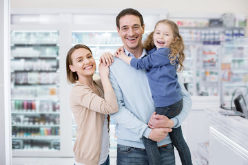 Family together. Exuberant jolly family coming in drugstore and smiling to camera