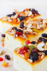 Three piece of Fruitcake topped with mix fruits and Cashew nuts on wooden cutting board