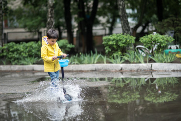 A wet child is jumping in a puddle. Fun on the street. Tempering in summer