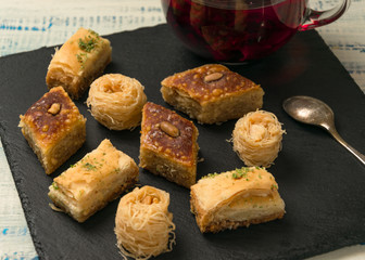 Oriental sweets and red fruit tea on black stone.