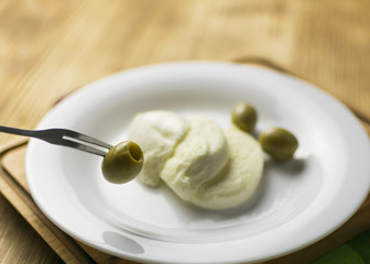 Cheese mozzarella and olives on a plate on a wooden background.