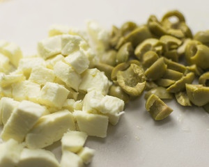 Sliced mozzarella cheese and olives. Preparing for making salad.