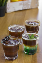 Cold coffees with mint leaves, orange, amarena fruits and ice cubes