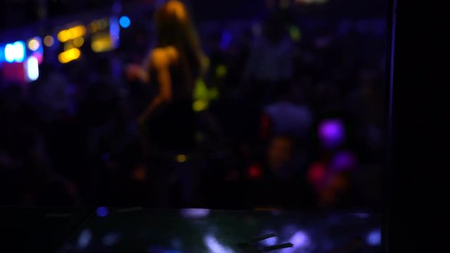 Long haired go-go dancer performing on stage at crowded night club, celebration