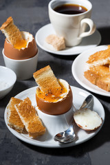 soft boiled egg, toasts and coffee for breakfast on dark background, top view