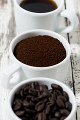 Three types of coffee - ground, grain and beverage in cups on white table, closeup