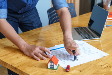 Estate agent stamping the document on wooden desk: real estate, home loan and insurance concept.