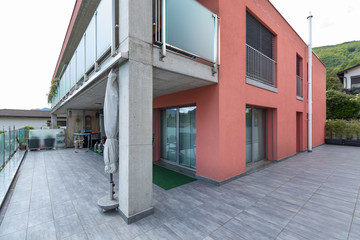 Red building exterior with large terrace and glass parapet