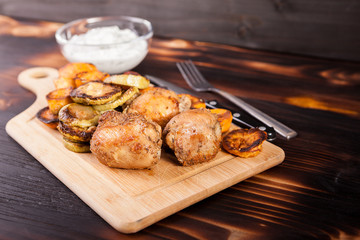 Fried chicken meat and grilled vegetables on wooden table