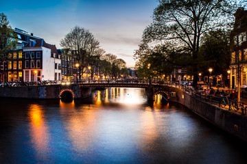 Night view with bridge, bicycles and water reflection in Amsterdam city, Netherlands