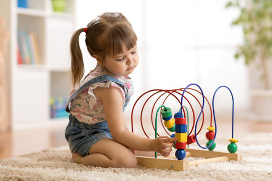 Child girl plays with educational toy indoors