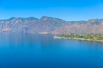 Fototapeta na wymiar View from Lake Atitlan in the early morning, blue skys and clear water, beautiful magic lake with volcanos and indigenous people in the highland of Guatemala 