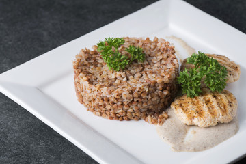 Buckwheat porridge with dietary meat on a white plate is tenderly served