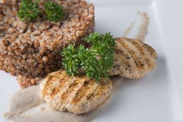 Buckwheat porridge with dietary meat on a white plate is tenderly served