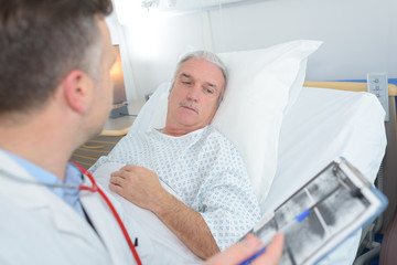 senior patient looking at x-ray with his doctor in hospital