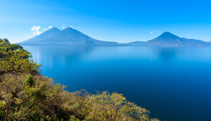 Naklejka na ściany i meble View from Lake Atitlan in the early morning, blue skys and clear water, beautiful magic lake with volcanos and indigenous people in the highland of Guatemala 